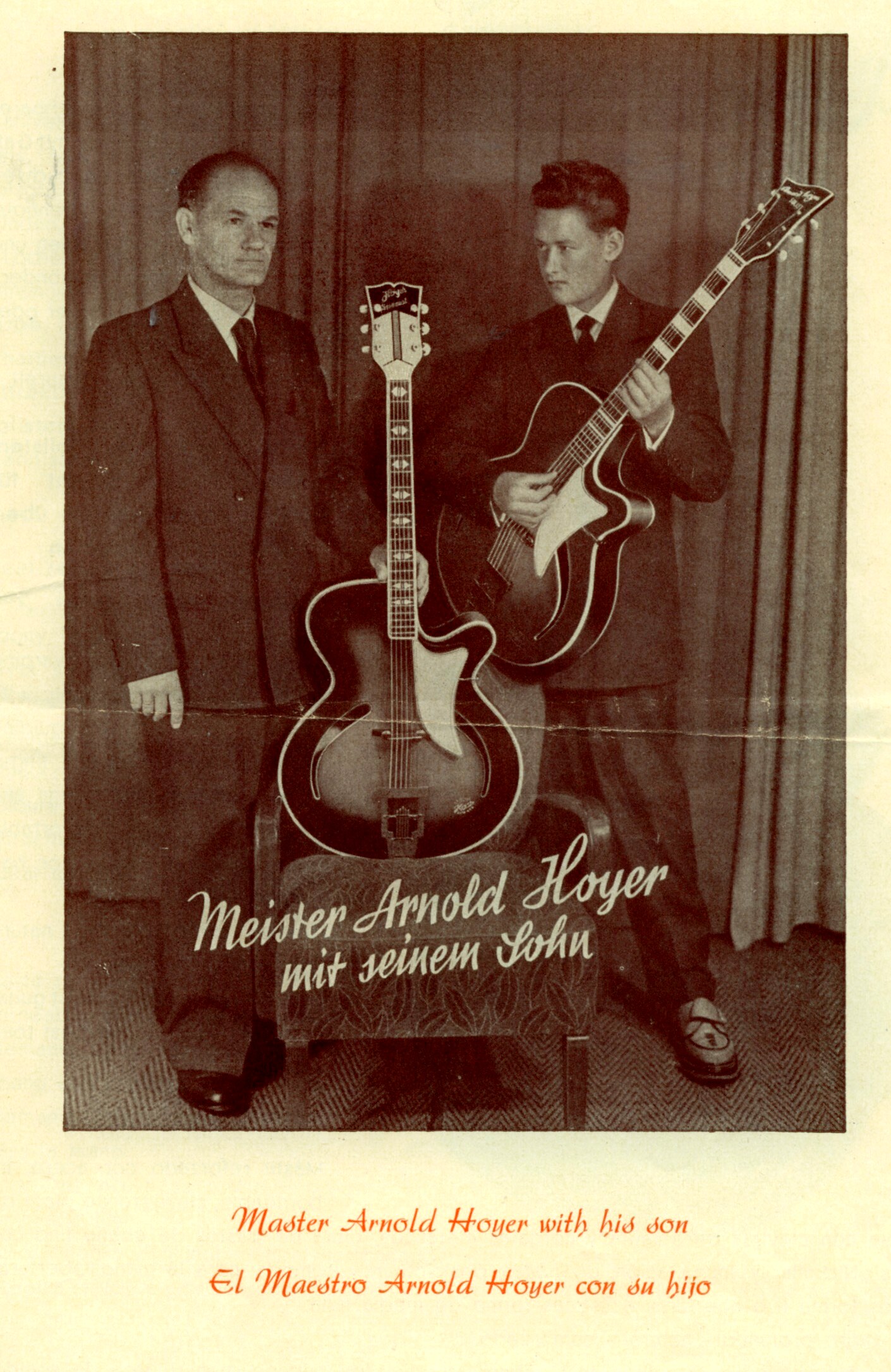 Sepia studio portrait of older Arnold Hoyer in a dark suit holding an upright archtop guitar, beside young Walter Hoyer in a suit holding a cutaway archtop, with trilingual caption “Master Arnold Hoyer with his son.”